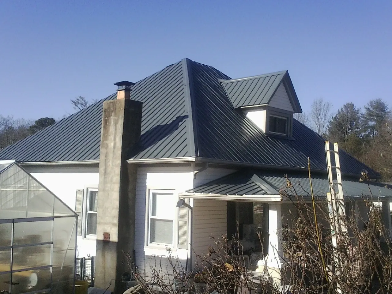 Dark blue standing seam metal roof on a white farmhouse with dormer — Slate & Tile Roof Repair by Roofing Brothers in Yamhill