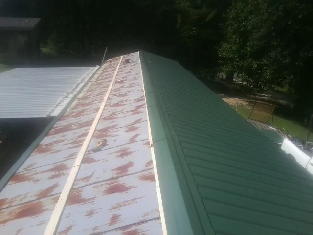 Old rusted panels beside newly installed green metal roofing — Wind Damage Roof Repair by Roofing Brothers in Yamhill