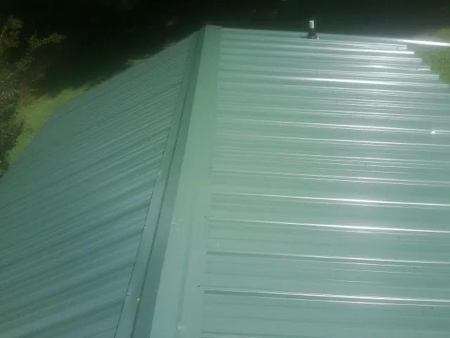 New green metal panels meeting at the ridge of a roof — Flat Roof Repair work by our crew in Yamhill