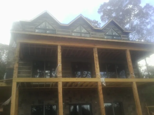 Dormers and porch framing on a large log home under construction — Roof Coating work by our crew in Yamhill