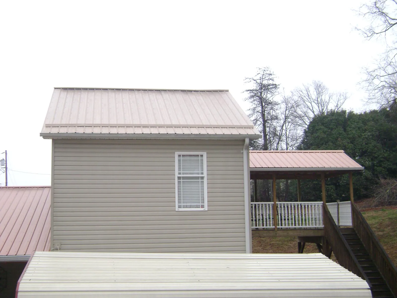 Tan metal roofs on a two story addition and attached porch, from a Roof Replacement job in Yamhill