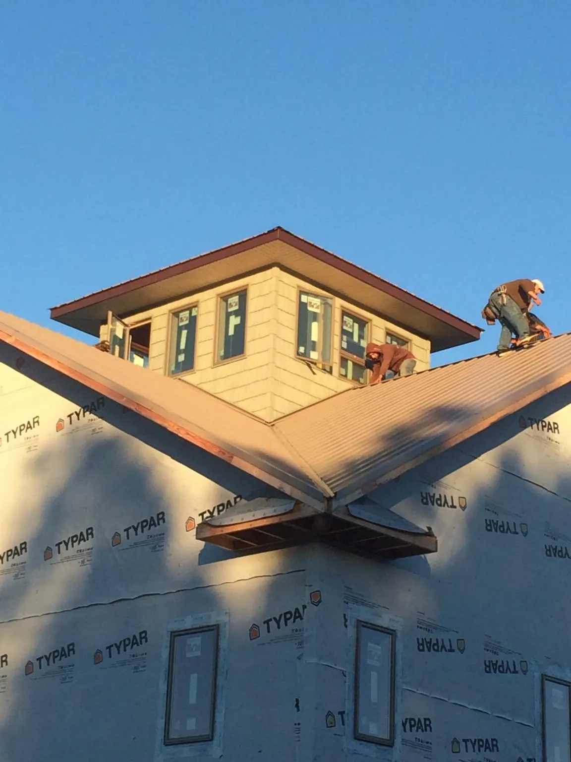 Roofers working around a rooftop cupola on a new metal roof at sunset — Roof Waterproofing in Yamhill by Roofing Brothers